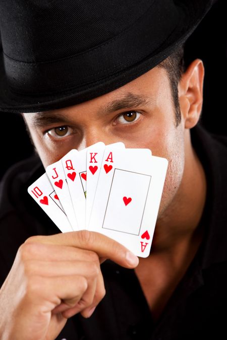 male magician covering his face with cards - isolated over black