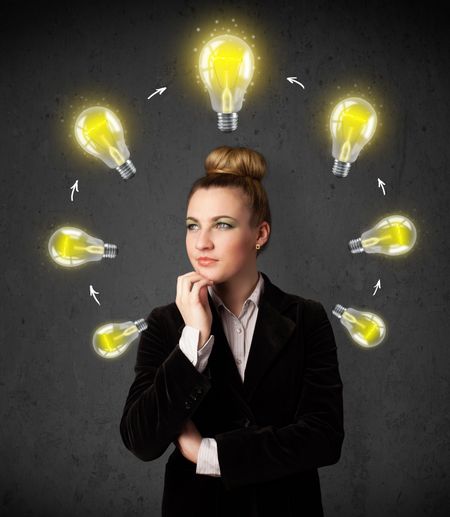 Thoughtful young woman with shining lightbulbs circulating around her head