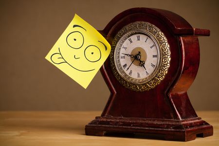 Drawn smiley face on a post-it note sticked on an alarm clock
