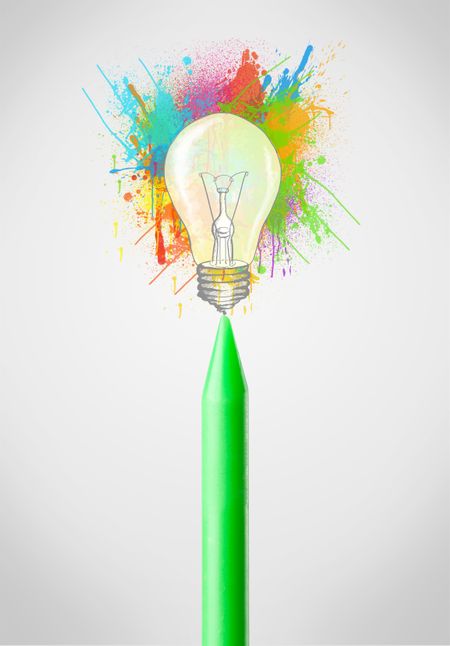 Colored crayon close-up with colored paint splashes and lightbulb concept