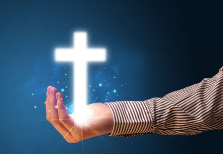 Young businessman holding a glowing cross in his hand