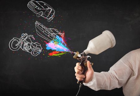 man-airbrush-spray-paint-car-boat-225890461 Man with airbrush spray paint with car, boat and motorcycle drawing on dark background