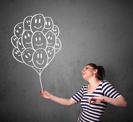 Young woman holding a bunch of smiling balloons