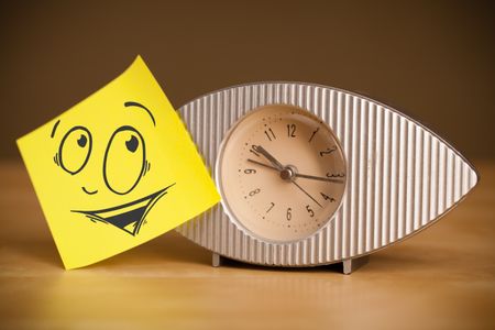 Drawn smiley face on a post-it note sticked on alarm clock