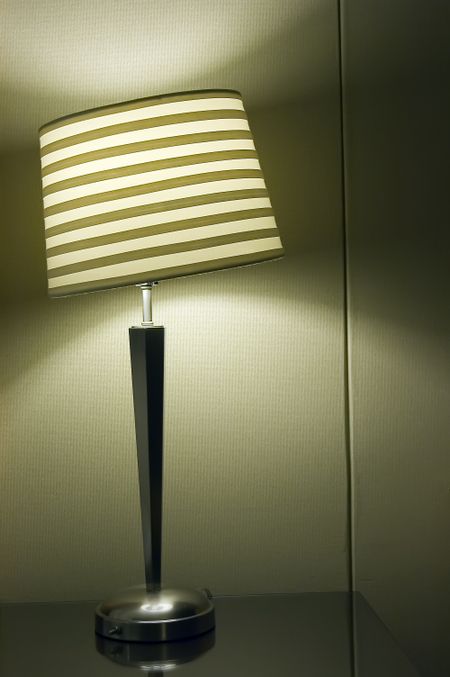 Lamp with skewed shade on night table in hotel room