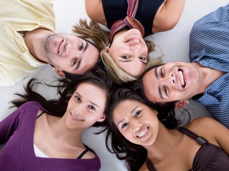 happy group of friends smiling with their heads together on the floor isolated