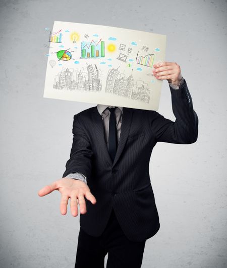 Businessman holding a paper in front of his head with charts and cityscape drawing