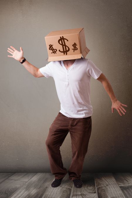 Young man standing and gesturing with a cardboard box on his head with dollar signs