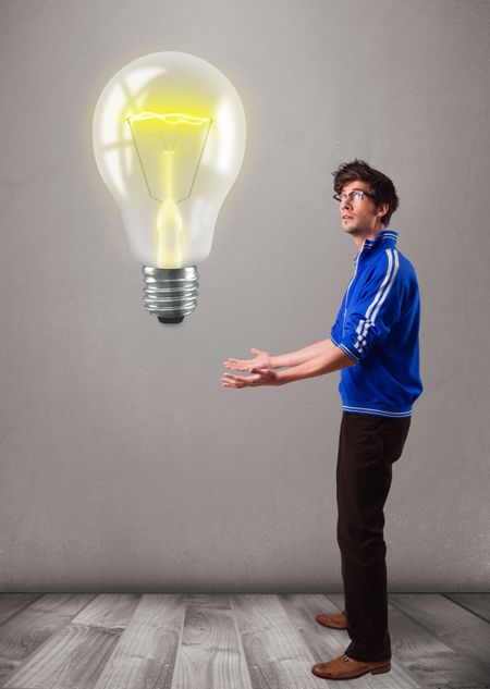 Attractive young man holding realistic 3d light bulb