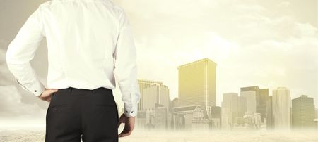 Businessman from the back in front of a city view with sunshine