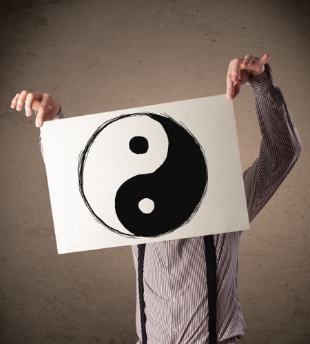 Businessman holding a paper with a yin-yang symbol on it in front of his head