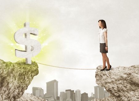 Businesswoman standing on the edge of mountain with a shining dollar mark on the other side 