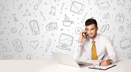 Businessman sitting at table with hand drawn media icons and symbols