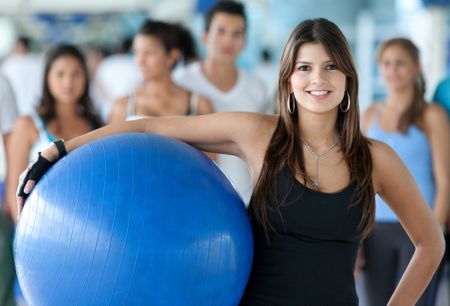 Gym woman with a pilates ball standing in front of a group