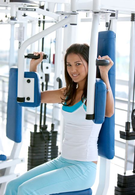 woman at the gym doing back exercises on a machine