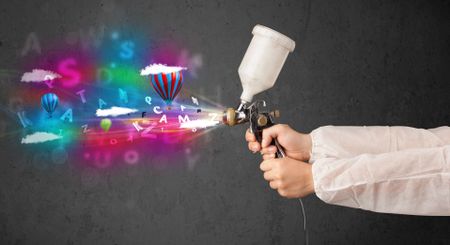 Worker with airbrush and colorful abstract clouds and balloons concept