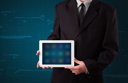 Young businessman holding a white modern tablet with blurry apps