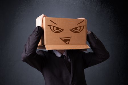 Businessman standing and gesturing with a cardboard box on his head with evil face