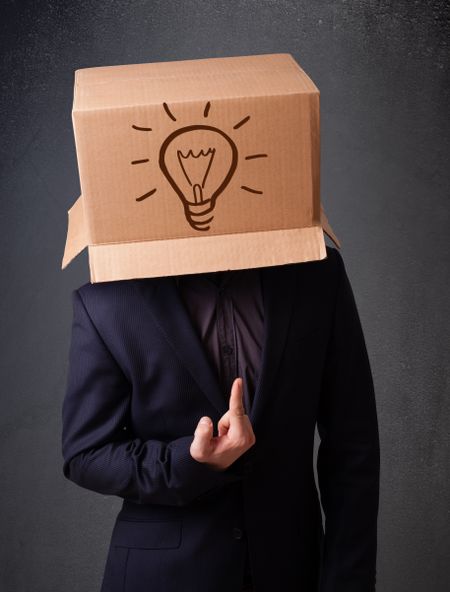 Young man standing and gesturing with a cardboard box on his head with light bulb