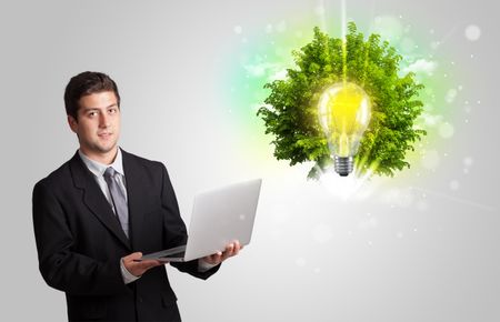 Young man presenting idea light bulb with green tree concept