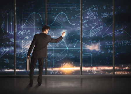 Businessman drawing business graphs on glass wall 