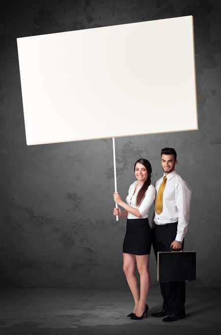 Young business couple holding a blank whiteboard