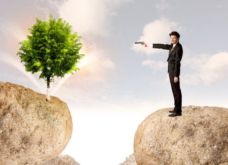Businessman standing on the edge of rock mountain with a tree on the other side 