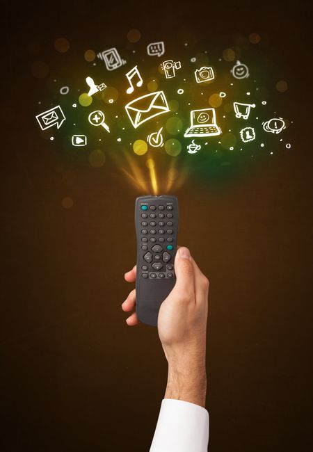 Hand holding a remote control, social media icons coming out of it 