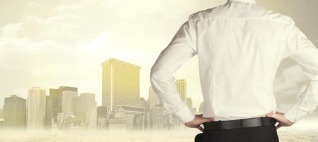 Businessman from the back in front of a city view with sunshine