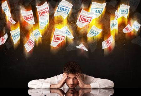 Depressed businessman sitting under falling papers