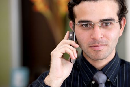 business man portrait in an office smiling and talking on the phone