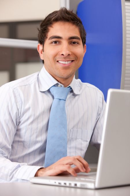 business man looking happy on a laptop in an office