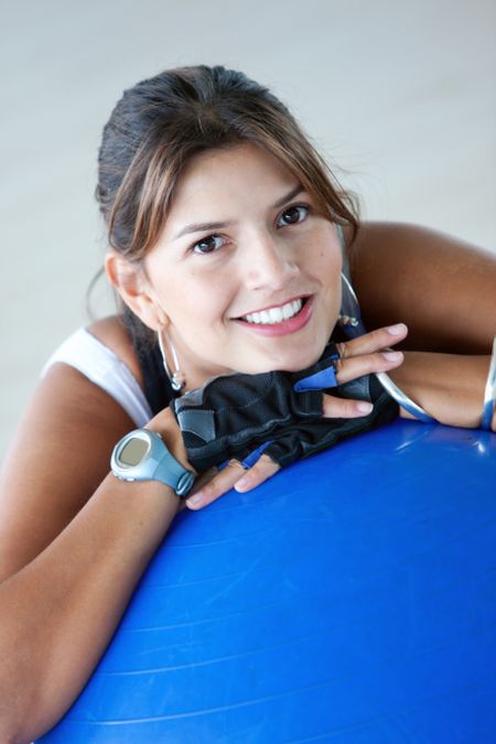 beautiful woman portrait at the gym smiling leaning on a pilates ball