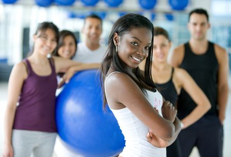 Beautiful black woman smiling at the gym with her friends behind her
