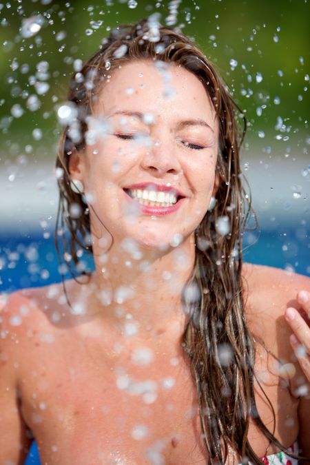 Beautiful woman refreshing her face with a water splash