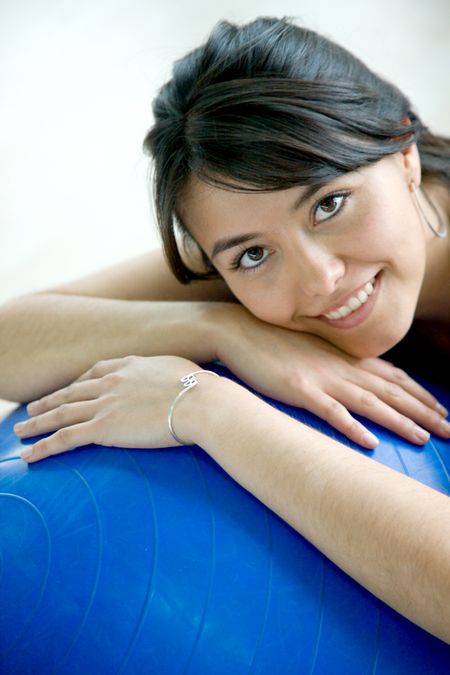 beautiful woman portrait at the gym smiling leaning on a pilates ball