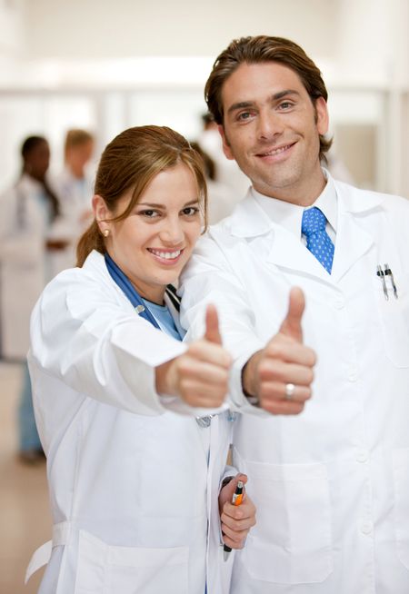 couple of doctors smiling at the hospital with thumbs up