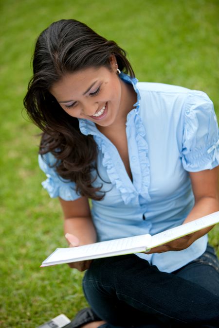 Beautiful woman smiling and studying outside with a notebook