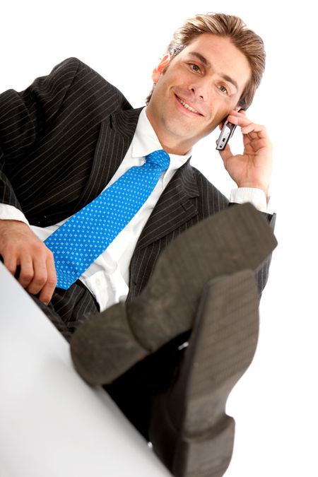 Confident businessman on the phone with his feet on the table - isolated