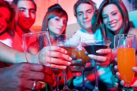 Group of happy friends at a bar or a nightclub toasting