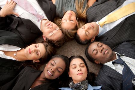 business group with heads together on the floor and their eyes closed  in an office
