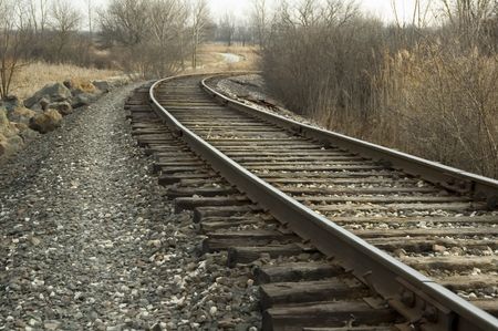 Railroad tracks curving in one direction, bike path in another