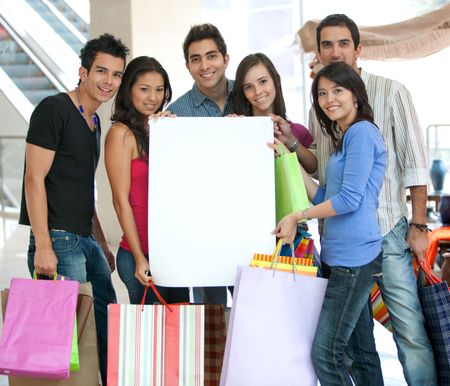 Group of shoppers holding a banner ad and some bags in a shopping mall