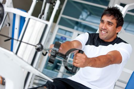 man at the gym doing exercise on a machine with weight