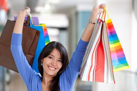 Shopping woman smiling in a mall with some bags