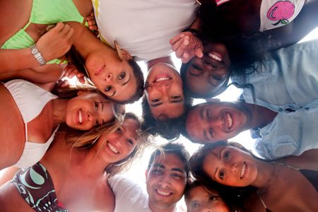 Happy group of friends at the beach with their heads together