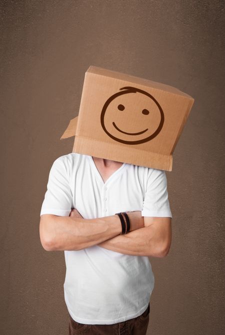 Young man standing and gesturing with a cardboard box on his head with smiley face