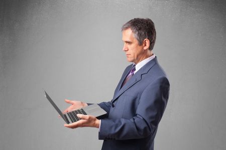Handsome businessman in suit holding modern laptop