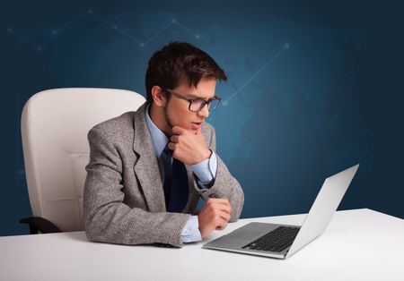 Attractive young man sitting at desk and typing on laptop