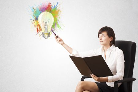 Young lady drawing a colorful light bulb with colorful splashes on white background